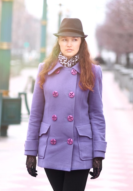 Bella ragazza con un cappello alla moda e guanti che cammina per strada