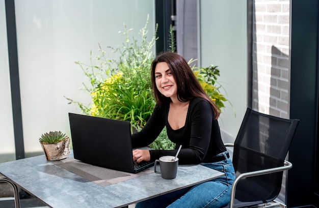 bella ragazza con un computer portatile si siede a un tavolo e lavora