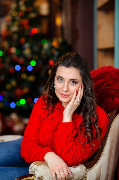 Bella ragazza con un maglione rosso vicino all'albero di Natale
