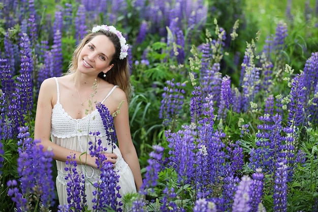 Bella ragazza con un mazzo di fiori blu sulla natura in estate