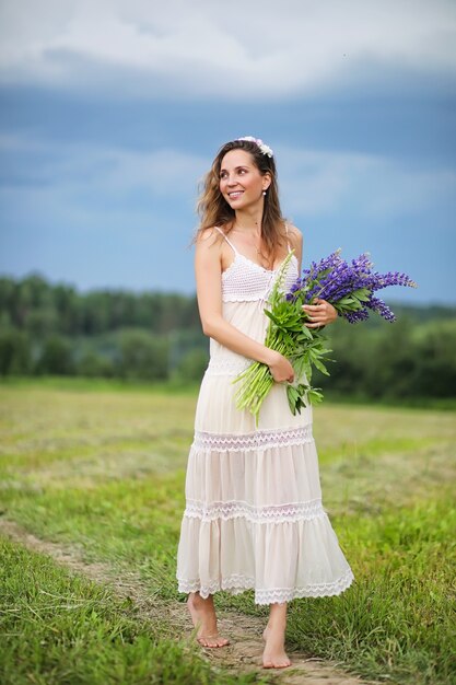 Bella ragazza con un mazzo di fiori blu sulla natura in estate