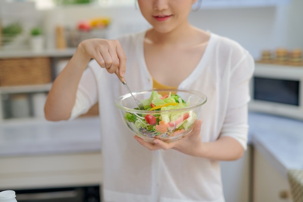 Bella ragazza con un piatto di insalata di vitamine fresche di verdure