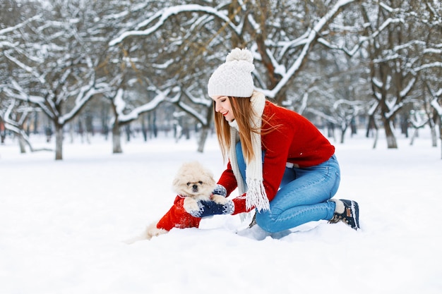 Bella ragazza con un simpatico cane che cammina in un parco invernale