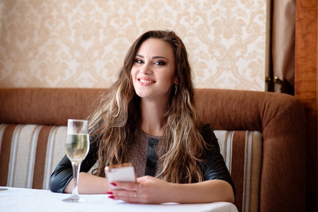 Bella ragazza con un telefono a un tavolo nel ristorante.