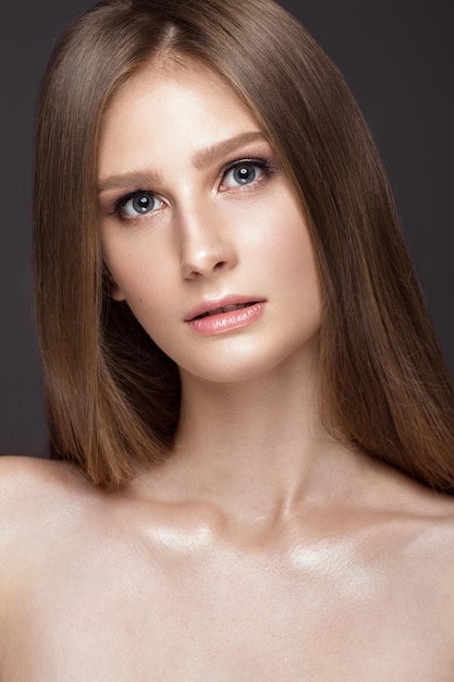 Bella ragazza con un trucco naturale leggero e una pelle perfetta. Volto di bellezza. Foto scattata in studio su sfondo grigio.