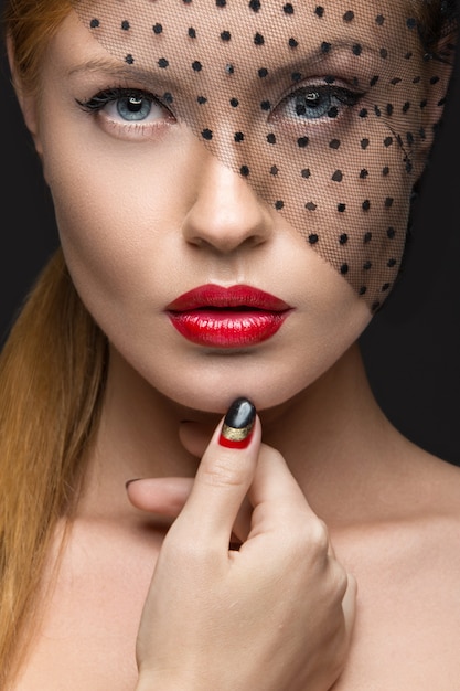 Bella ragazza con un velo, trucco da sera, unghie nere e rosse