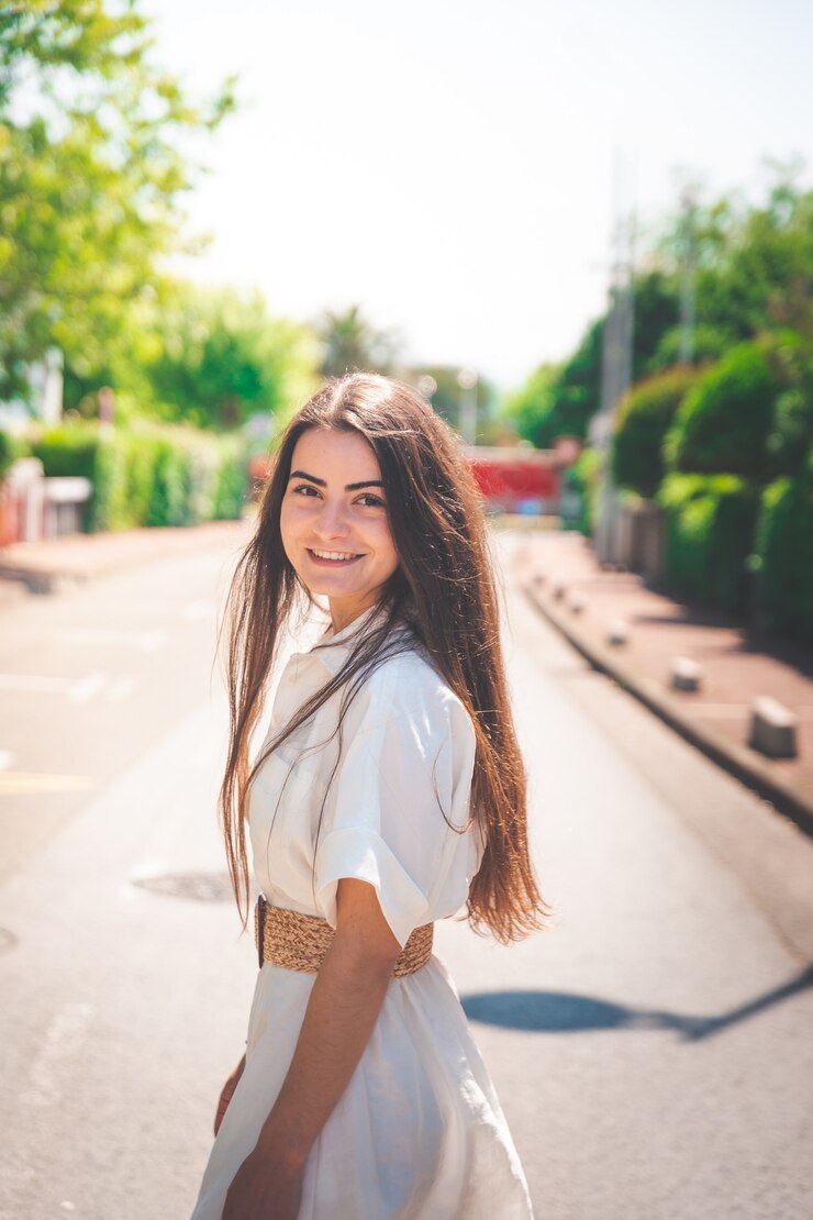 Bella ragazza con un vestito bianco che cammina attraverso un villaggio della costa