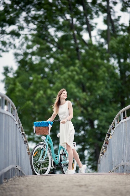 Bella ragazza con una bici blu