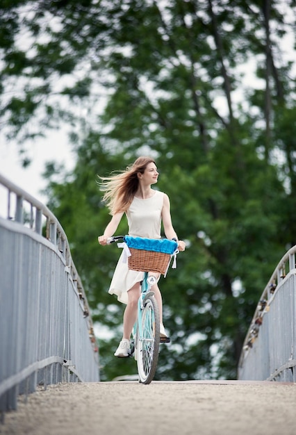 Bella ragazza con una bici blu