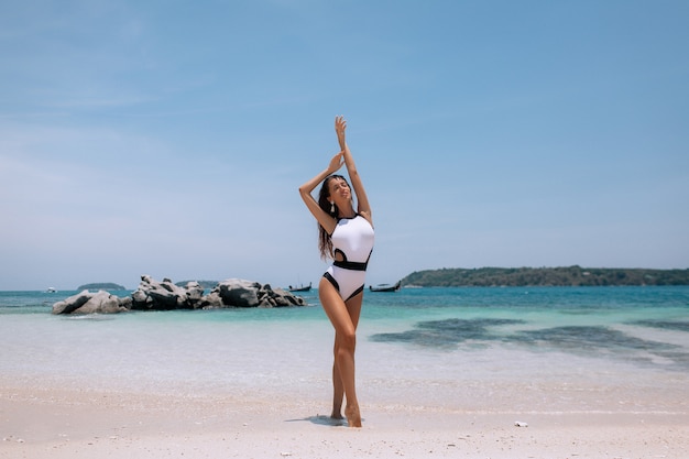 Bella ragazza con una figura snella in un bikini in posa sulla spiaggia.