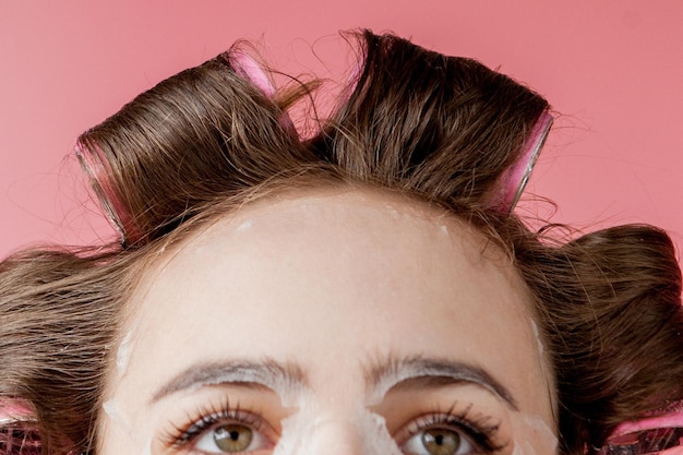 Bella ragazza con una maschera e bigodini toccando il suo viso