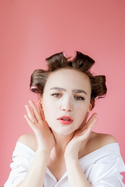 Bella ragazza con una maschera e bigodini toccando il suo viso