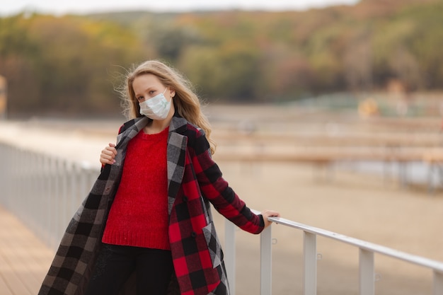 Bella ragazza con una maschera protettiva e un cappotto