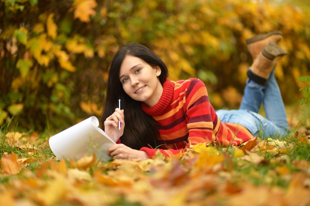 Bella ragazza con una nota nel parco autunnale