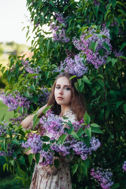 Bella ragazza dagli occhi grandi vicino all'albero lilla.