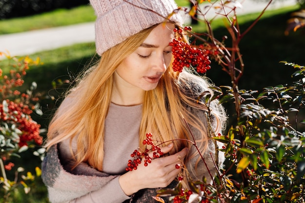 Bella ragazza dai capelli biondi, che cammina con un cappello rosa in giardino, si gode la natura e una giornata primaverile