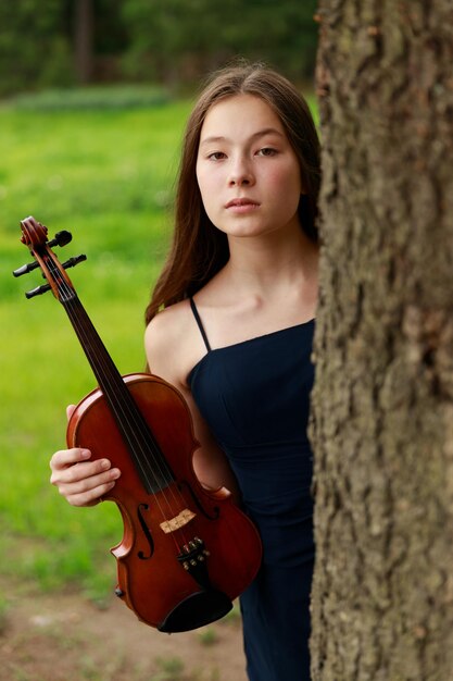 Bella ragazza dai capelli castani di aspetto asiatico con un violino in natura. musicista in natura. musica classica. Foto di alta qualità