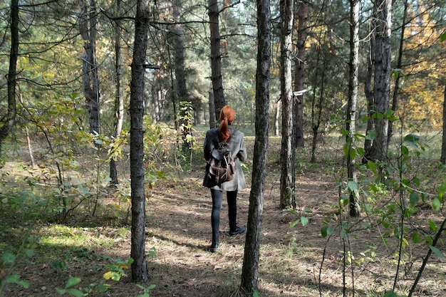 Bella ragazza dai capelli rossi attiva che cammina nel bosco. Boschi freschi all'aperto, concetto di stile di vita sano di benessere. Donna libera che respira aria pulita nella foresta naturale