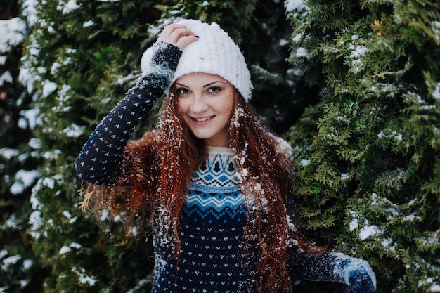 Bella ragazza dai capelli rossi nel parco invernale con la neve