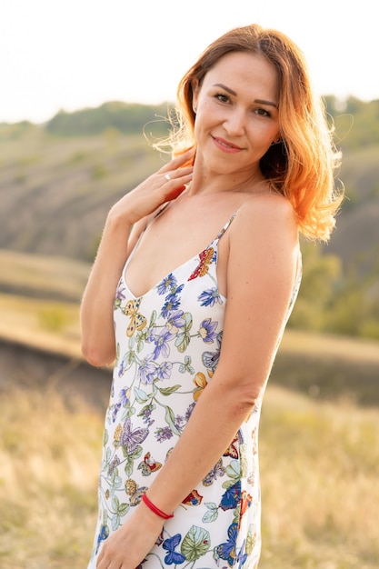 Bella ragazza dai capelli rossi si diverte e balla in un campo al tramonto.