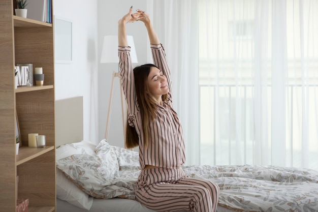 Bella ragazza di buon umore in pigiama in camera da letto