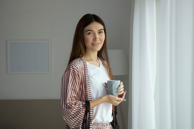 Bella ragazza di buon umore in pigiama in camera da letto