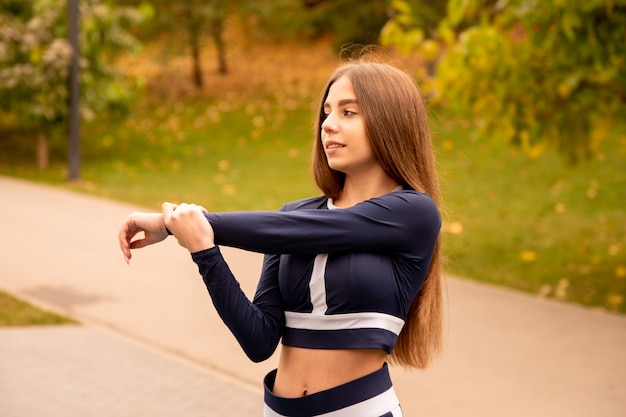 Bella ragazza di formazione. Ragazza sportiva in abiti sportivi. Allunga le braccia.