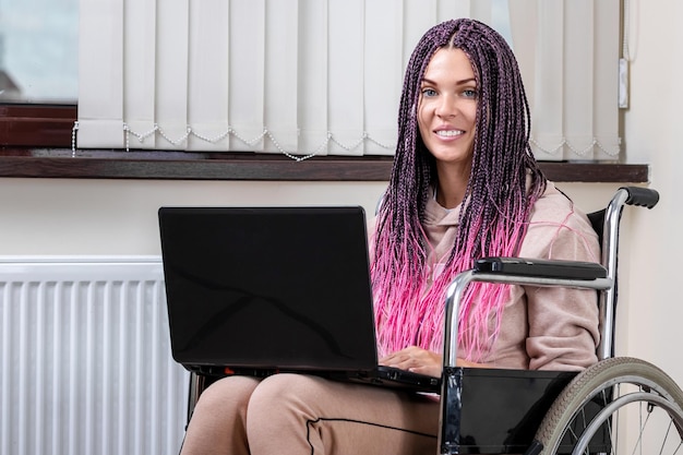 Bella ragazza disabile moderna che lavora su un laptop su una sedia a rotelle Lavoro da casa lavoro per il lavoro a distanza freelance disabili