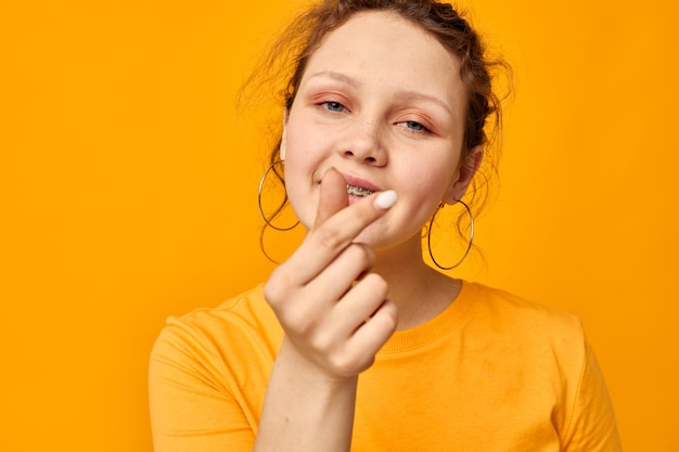 Bella ragazza divertente orecchini grimace gesto della mano Lo stile giovanile ha isolato gli sfondi inalterati