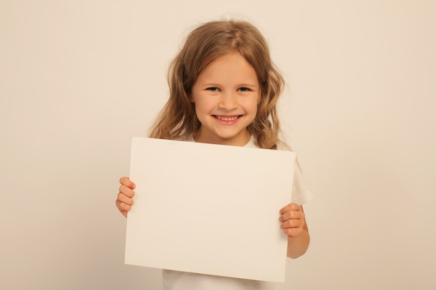 bella ragazza dolce e felice con i capelli lunghi in una maglietta bianca tiene in mano un lenzuolo bianco