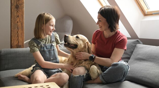 Bella ragazza e bambino preadolescente famiglia carezza golden retriever cane seduto sul divano madre e