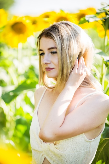 Bella ragazza europea in un vestito bianco sulla natura con i girasoli