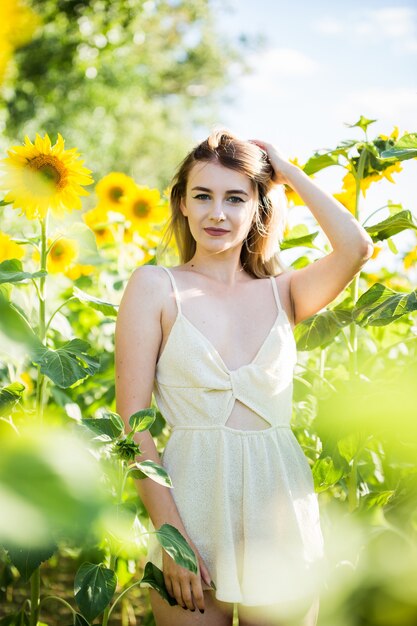 Bella ragazza europea in un vestito bianco sulla natura con i girasoli