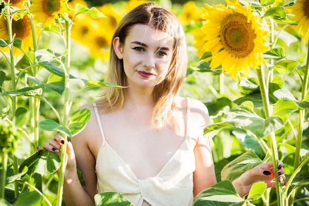 Bella ragazza europea in un vestito bianco sulla natura con i girasoli