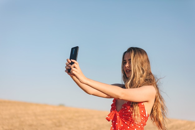 Bella ragazza fa un selfie all'aperto in un tramonto estivo