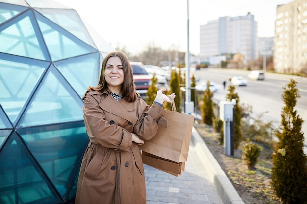 Bella ragazza felice che cammina con la borsa della spesa per le strade della città mentre si fa shopping Ragazza alla moda sorridente che cammina lungo la strada