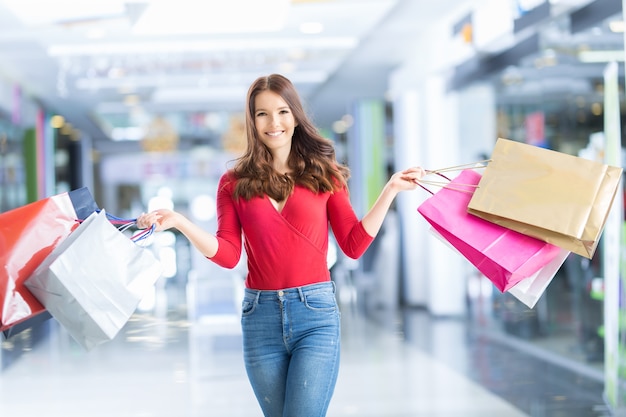 Bella ragazza felice con carta di credito e borse della spesa nel centro commerciale