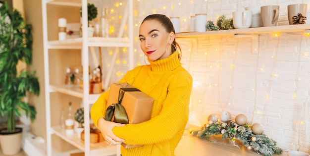 Bella ragazza felice con i regali di Natale della cucina di Capodanno