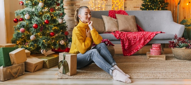 Bella ragazza felice con i regali di Natale di un albero di Capodanno