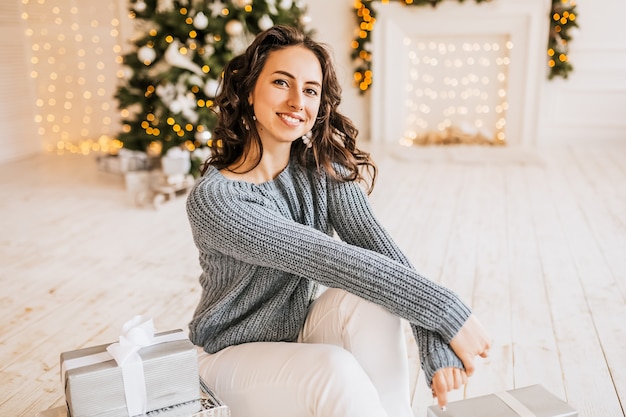 Bella ragazza felice con i regali di Natale di un albero di Capodanno