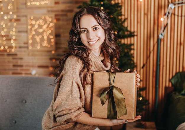 Bella ragazza felice con i regali di Natale di un albero di Capodanno