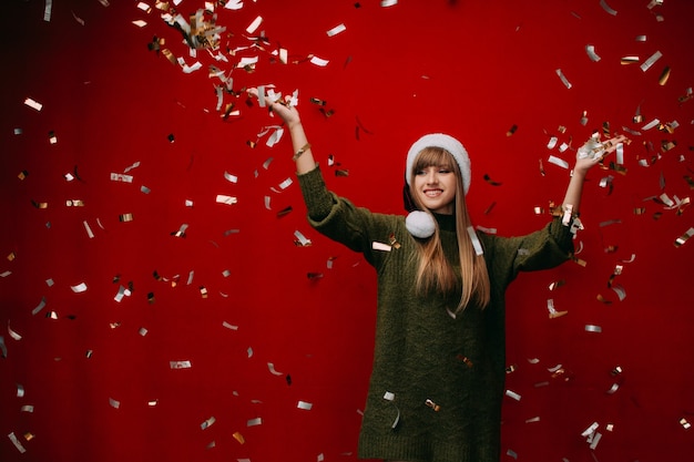 Bella ragazza felice con un cappello da Babbo Natale lancia coriandoli Promozione o sconto di Capodanno