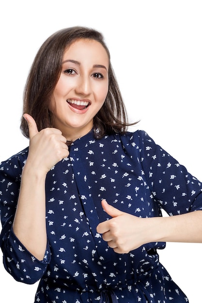 Bella ragazza felice con un sorriso felice mostra due pollici in su guardando la fotocamera, felicità la camicia blu isolare lo sfondo bianco