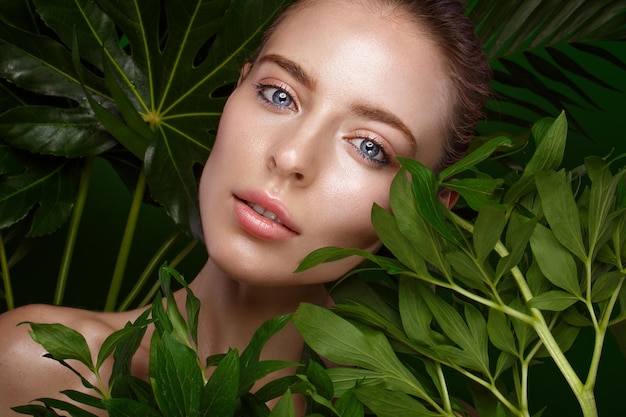Bella ragazza fresca con trucco naturale della pelle perfetta e foglie verdi Bellezza viso