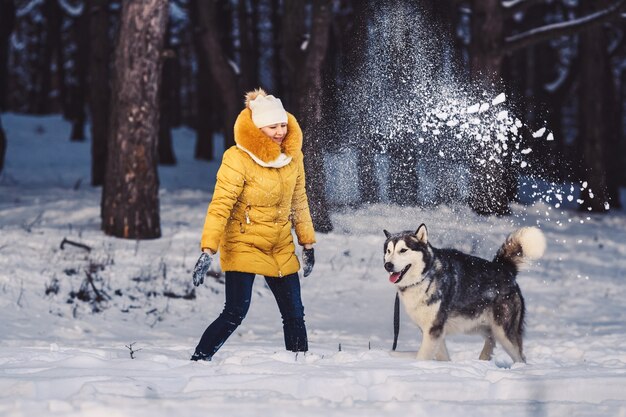 Bella ragazza giovane divertente che gioca con il suo cane in inverno nel parco