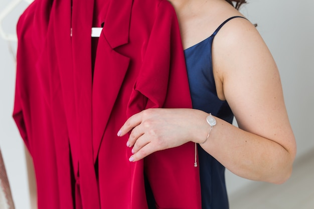 Bella ragazza guardando il vestito mentre si sceglie quello adatto. Moda, vendita e concetto di negozio.