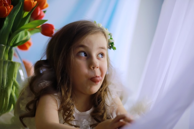 Bella ragazza in abiti bianchi con un magnifico bouquet dei primi tulipani. Giornata internazionale della donna. Ragazza con i tulipani.