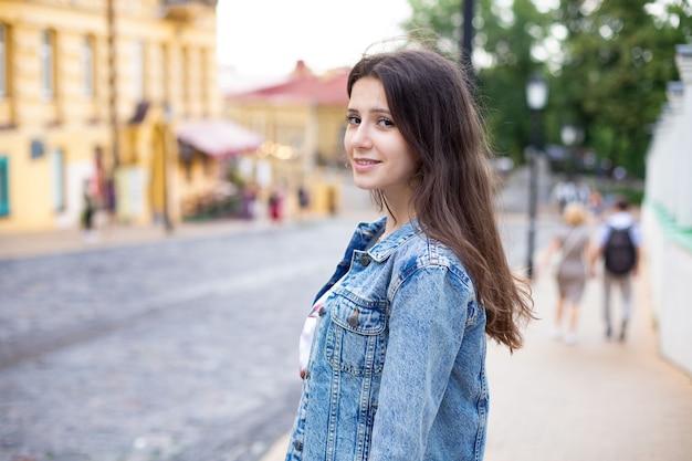 Bella ragazza in abiti casual guarda la telecamera e sorride mentre si trova in mezzo alla strada. giornata mondiale del turismo