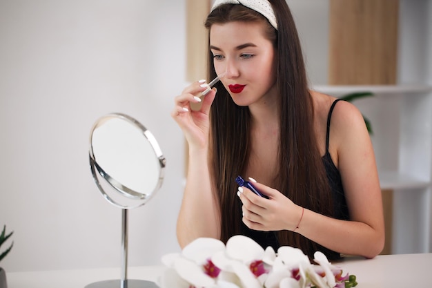 Bella ragazza in abiti da casa porta bellezza al viso davanti a uno specchio