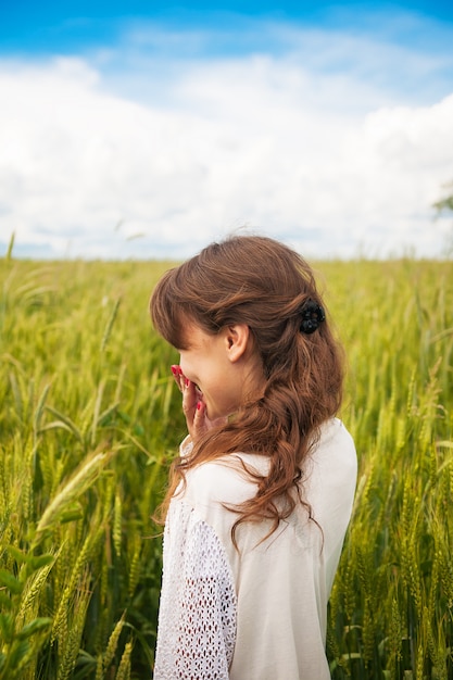 Bella ragazza in abito bianco in piedi in un campo di grano